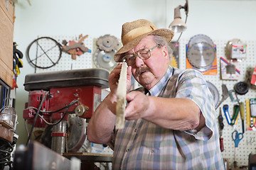 Image showing Senior man holding wooden plank