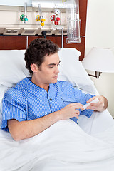 Image showing Patient sitting on bed reading medicine box