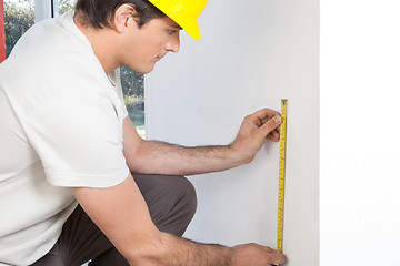 Image showing Young contractor measuring wall