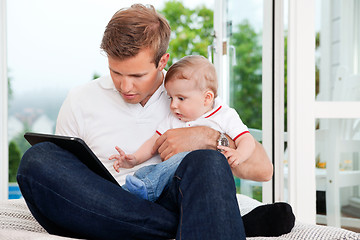 Image showing Man Using Digital Tablet while Holding Child