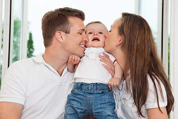 Image showing Parents kissing child