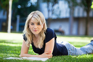 Image showing Girl lying on grass with a book
