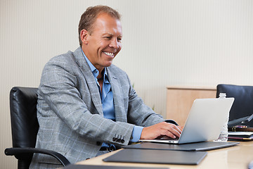 Image showing Cheerful businessman working on laptop