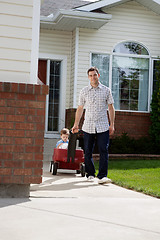 Image showing Father Pulling Son Sitting in Pram