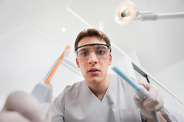 Image showing Young male holding dental tools