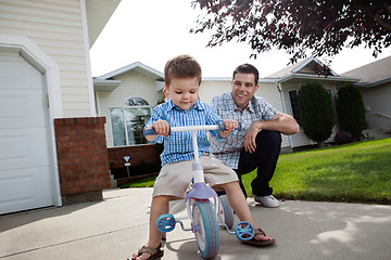 Image showing Father teaching Son To Ride a Tricycle