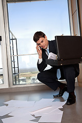 Image showing Man Bending Down to Collect Scattered Papers