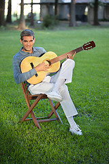 Image showing Man Playing Guitar Sitting in Lawn