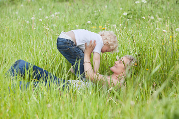 Image showing Mother lying on grass and playing with son