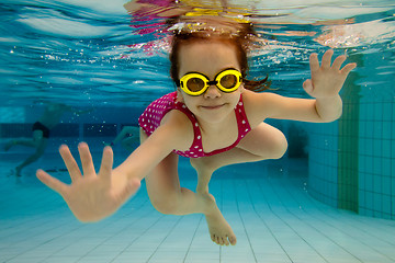 Image showing The girl smiles, swimming under water in the pool