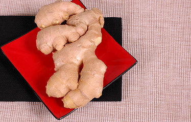 Image showing Hand of ginger on red plate and black napkin