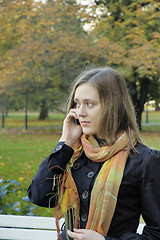 Image showing woman is talking on the phone in an autumnal Park 