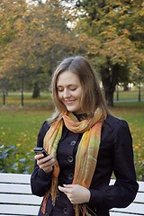 Image showing woman reads the message on phone in autumn park