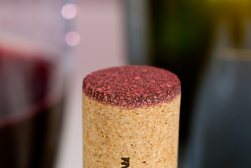 Image showing Red wine soaked cork in front of glass