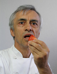 Image showing The chef is eating a piece of tomato