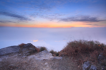 Image showing dark landscape with fog between hills and orange sky before sunr