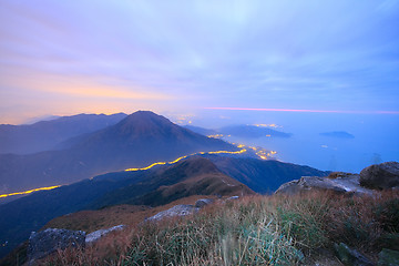 Image showing dark landscape with fog between hills and orange sky before sunr