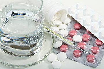 Image showing Different pills, glass of water and medical thermometer.