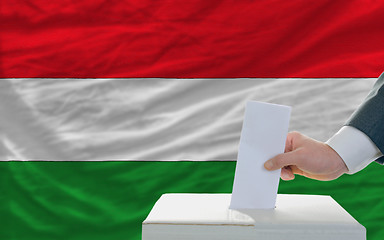 Image showing man voting on elections in hungary in front of flag