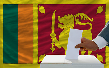 Image showing man voting on elections in srilanka in front of flag