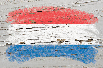 Image showing flag of Netherlands on grunge wooden texture painted with chalk 