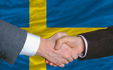 Image showing businessmen handshake after good deal in front of sweden flag