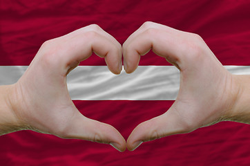 Image showing Heart and love gesture showed by hands over flag of latvia backg