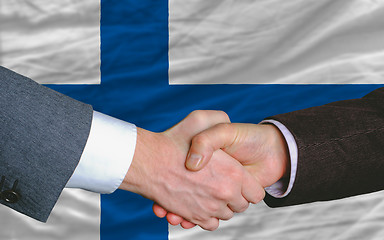 Image showing businessmen handshake after good deal in front of finland flag