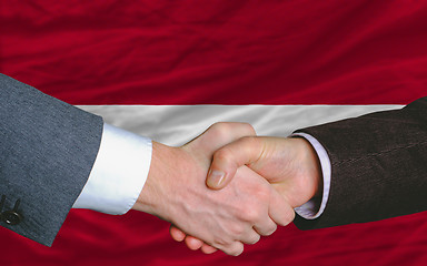 Image showing businessmen handshake after good deal in front of latvia flag