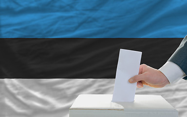 Image showing man voting on elections in estonia in front of flag