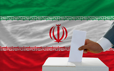 Image showing man voting on elections in iran in front of flag