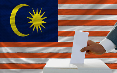 Image showing man voting on elections in malaysia in front of flag