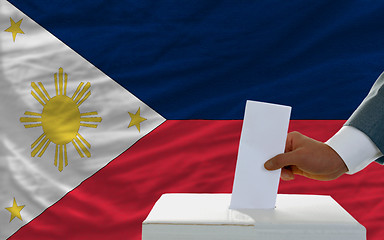 Image showing man voting on elections in phillipines in front of flag