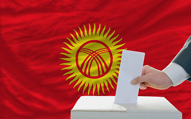 Image showing man voting on elections in kyrghyzstan in front of flag