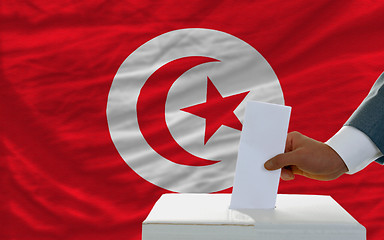 Image showing man voting on elections in tunisia in front of flag