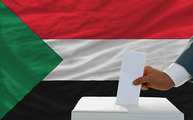 Image showing man voting on elections in sudan in front of flag