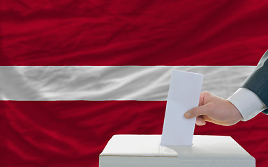 Image showing man voting on elections in latvia in front of flag