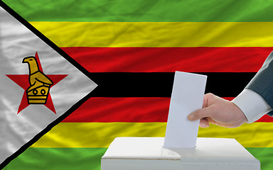 Image showing man voting on elections in zimbabwe in front of flag