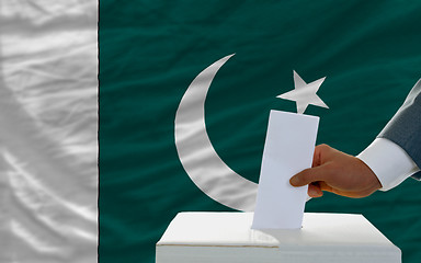 Image showing man voting on elections in pakistan in front of flag