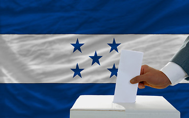 Image showing man voting on elections in honduras in front of flag