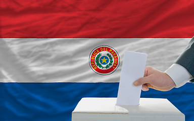 Image showing man voting on elections in paraguay in front of flag