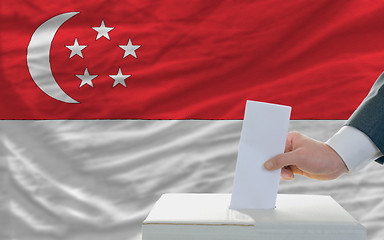 Image showing man voting on elections in singaporel in front of flag