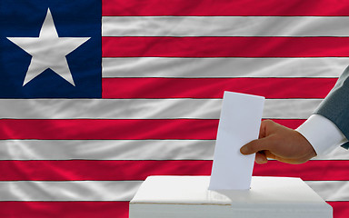 Image showing man voting on elections in liberia in front of flag