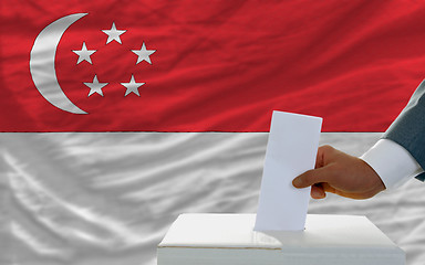 Image showing man voting on elections in singaporel in front of flag