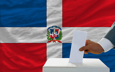 Image showing man voting on elections in dominican republic in front of flag