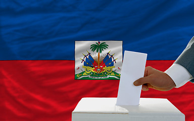 Image showing man voting on elections in haiti in front of flag