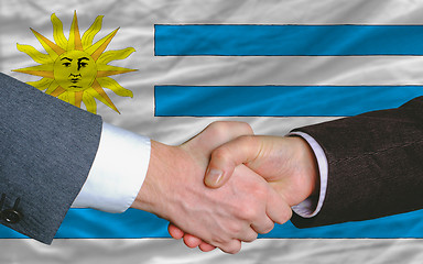 Image showing businessmen handshake after good deal in front of uruguay flag