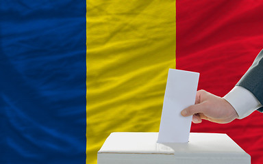 Image showing man voting on elections in romania in front of flag