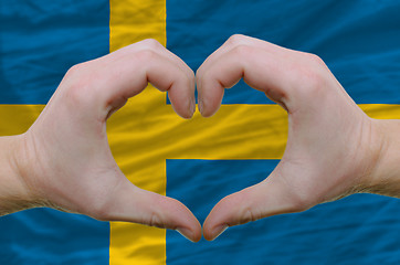 Image showing Heart and love gesture showed by hands over flag of sweden backg