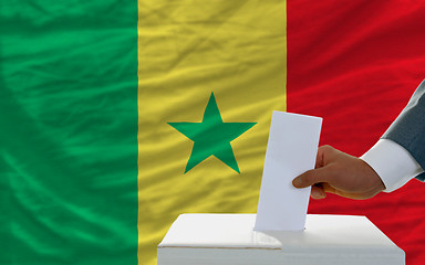 Image showing man voting on elections in senegal in front of flag